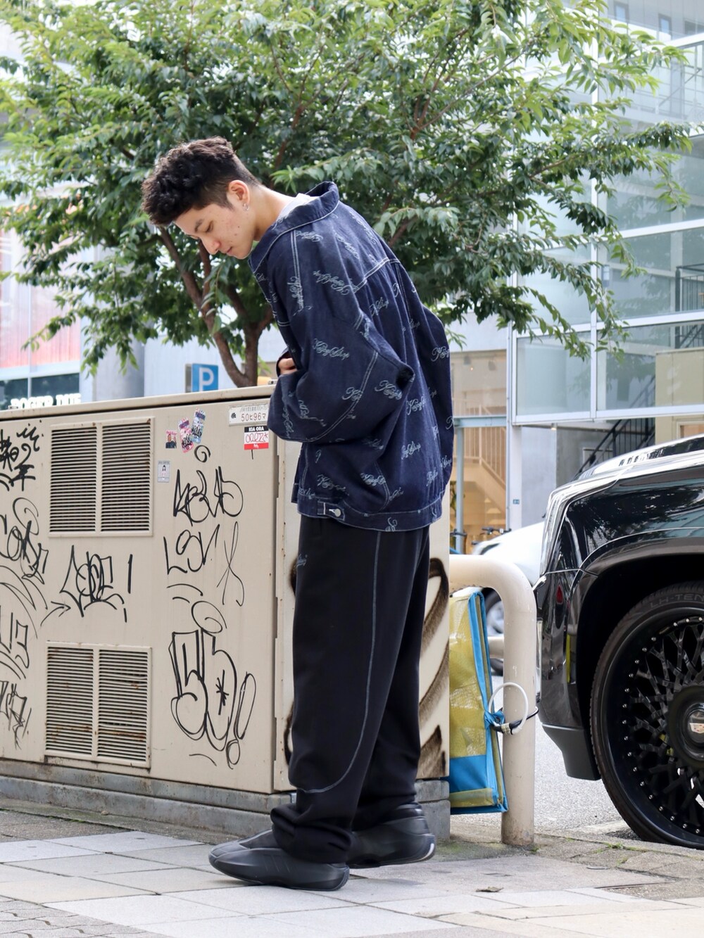 グレー系のTシャツ/カットソー、ブルー系のデニムジャケット、ブラック系のスウェットパンツを着用したメンズの秋コーディネートの3枚目の写真