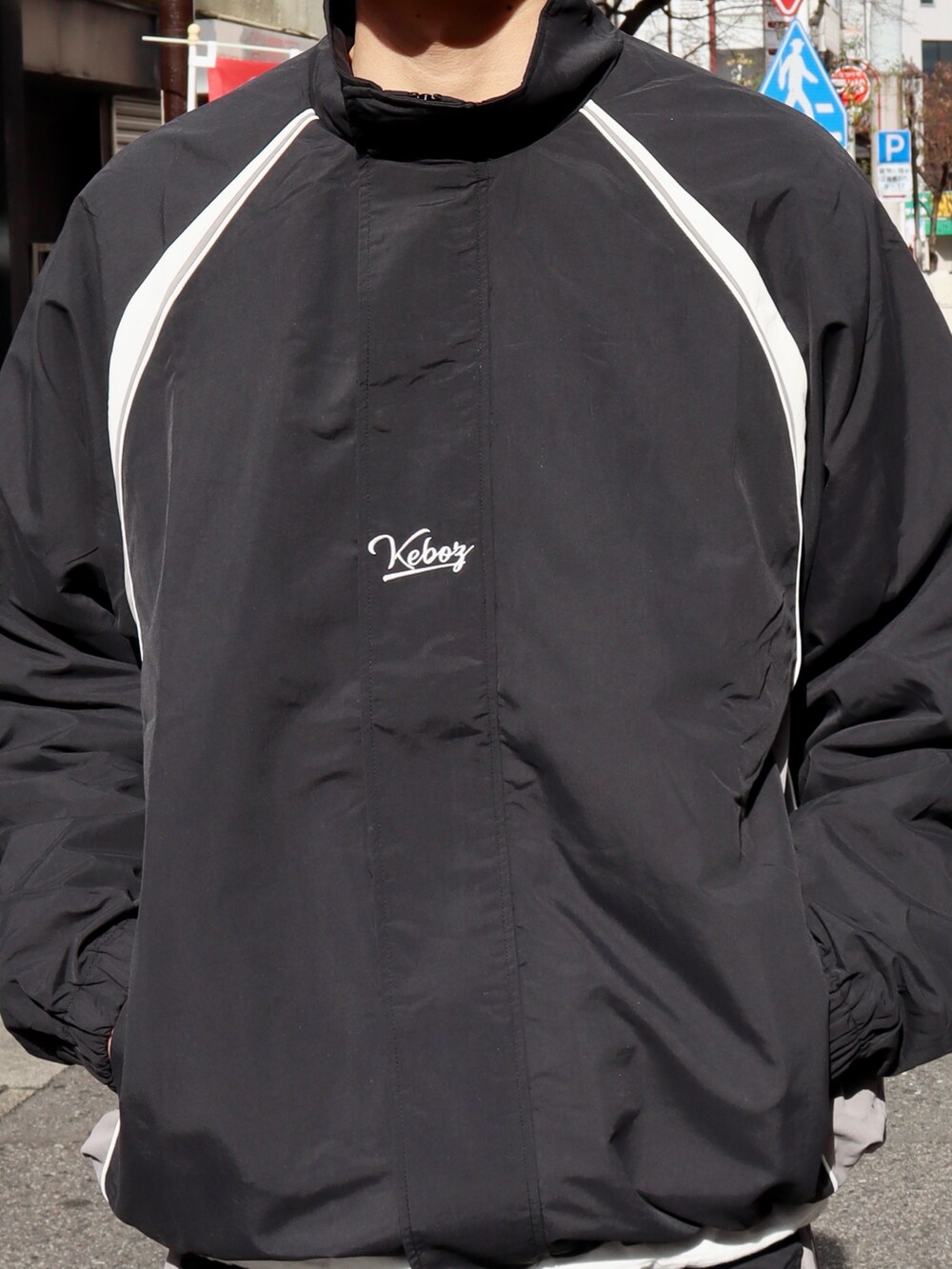 ブラック系のナイロンジャケット、ブラック系のその他パンツ、ブラック系のキャップを着用したメンズの冬コーディネートの5枚目の写真