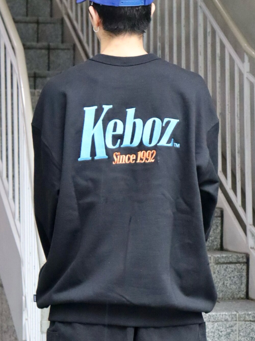 ブラック系のスウェット、ブラック系のカーゴパンツ、ブルー系のキャップを着用したメンズの秋コーディネートの3枚目の写真