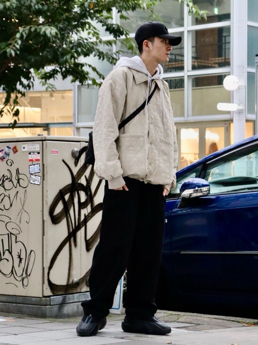 ベージュ系のブルゾン、グレー系のパーカー、ブラック系のカーゴパンツを着用したメンズの秋コーディネートの2枚目の写真