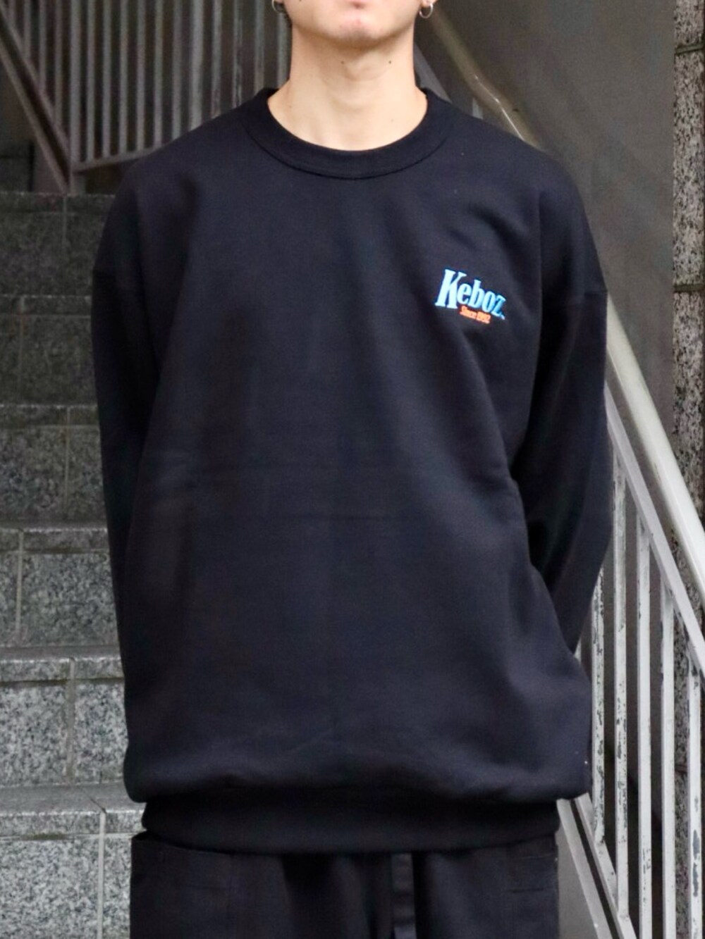 ブラック系のスウェット、ブラック系のカーゴパンツ、ブルー系のキャップを着用したメンズの秋コーディネートの2枚目の写真