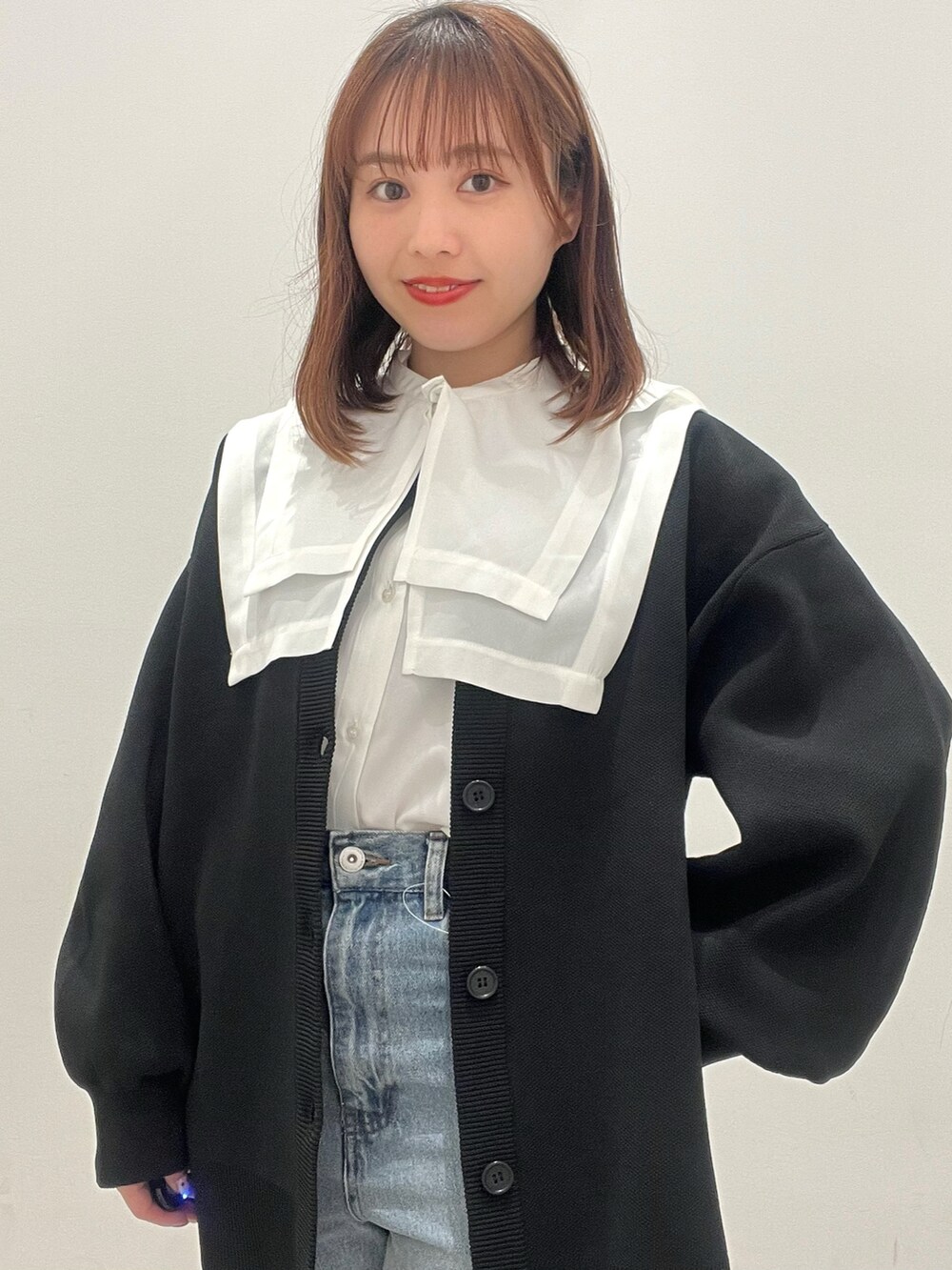 ホワイト系のシャツ/ブラウス、ブラック系のカーディガン/ボレロ、ブルー系のデニムパンツを着用したレディースの春コーディネートの2枚目の写真