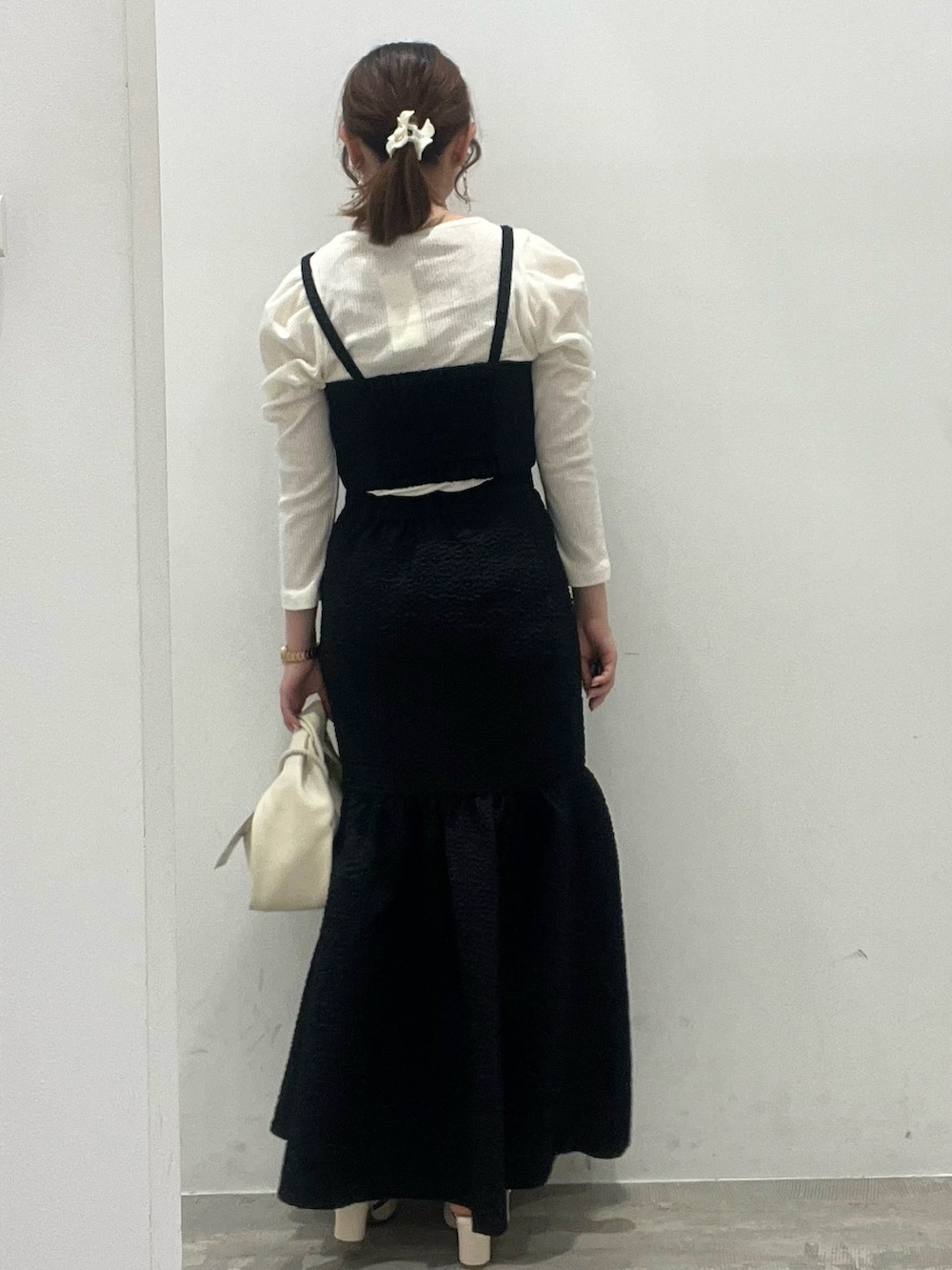 ブラック系のスカート、ブラック系のベスト、ホワイト系のショルダーバッグを着用したレディースの春コーディネートの4枚目の写真