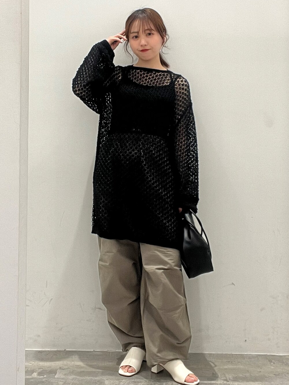 ブラック系のニット/セーター、グリーン系のその他パンツ、ブラック系のショルダーバッグを着用したレディースの春コーディネートの2枚目の写真