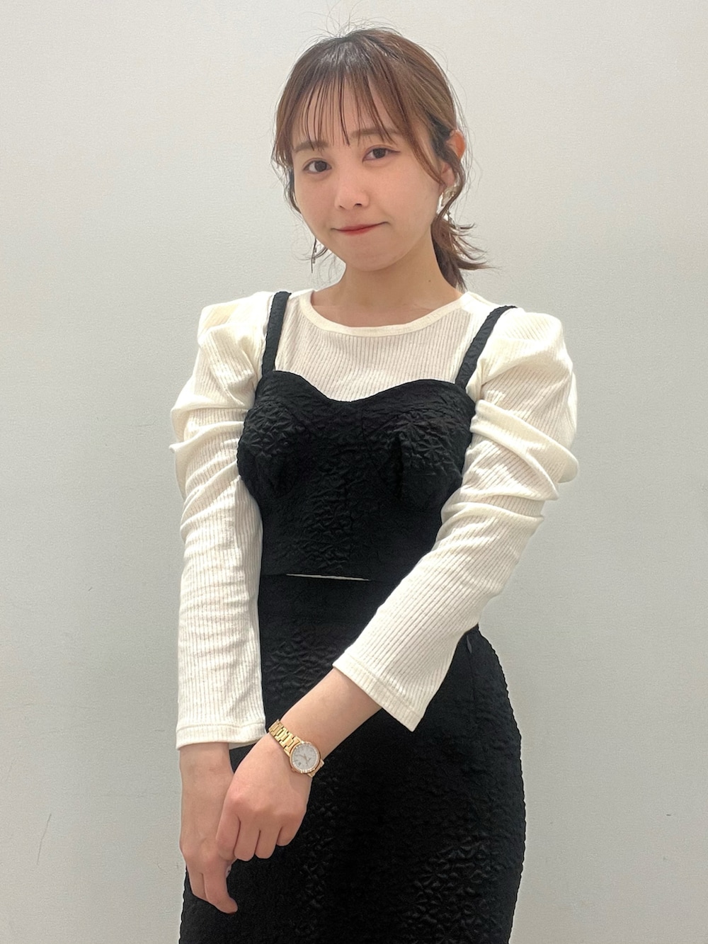 ブラック系のスカート、ブラック系のベスト、ホワイト系のショルダーバッグを着用したレディースの春コーディネートの2枚目の写真