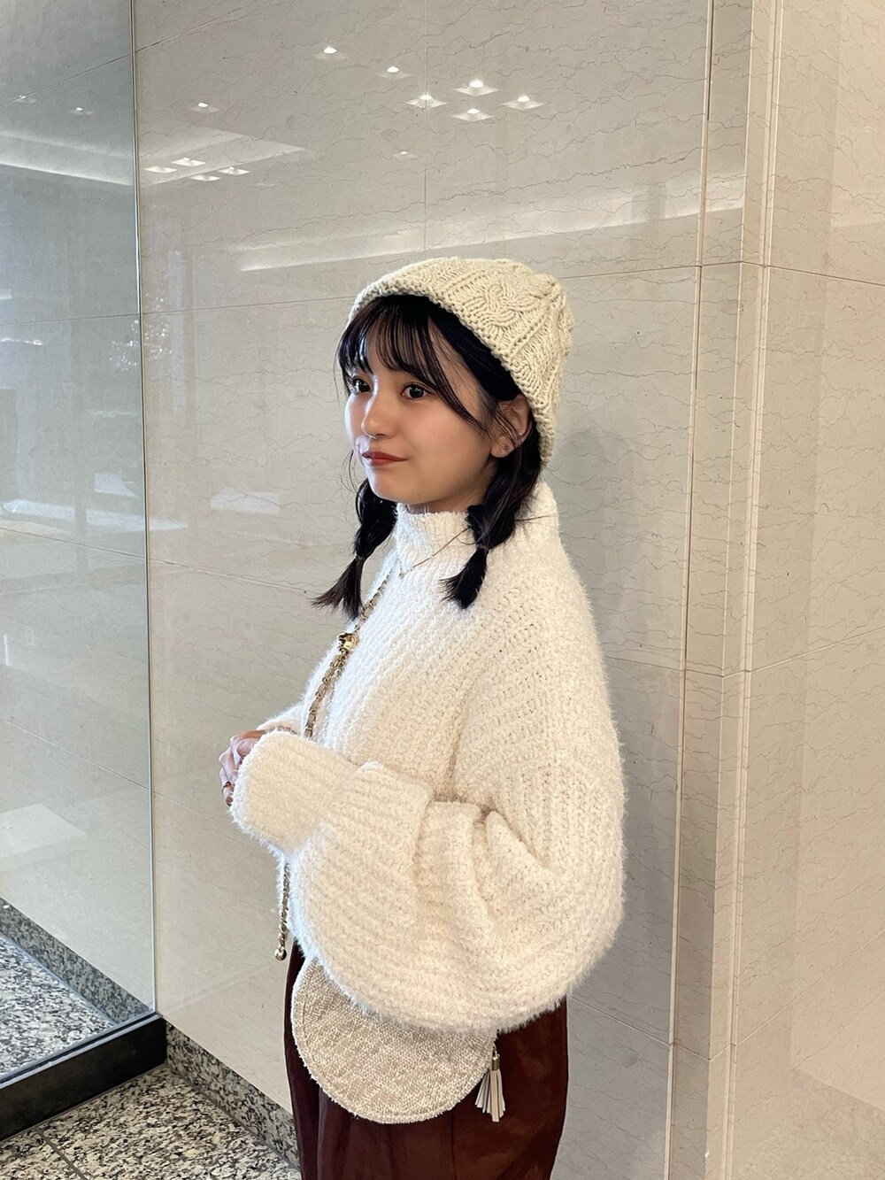 ホワイト系のニット/セーター、ブラウン系のその他パンツ、ベージュ系のショルダーバッグを着用したレディースの秋コーディネートの5枚目の写真