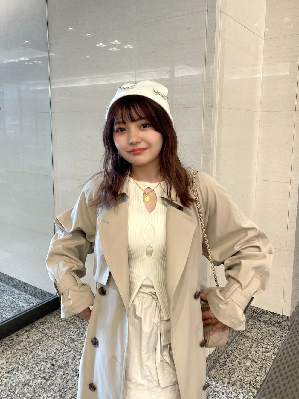 ベージュ系のトレンチコート、ホワイト系のニット/セーター、ベージュ系のショルダーバッグを着用したレディースの春コーディネートの4枚目の写真