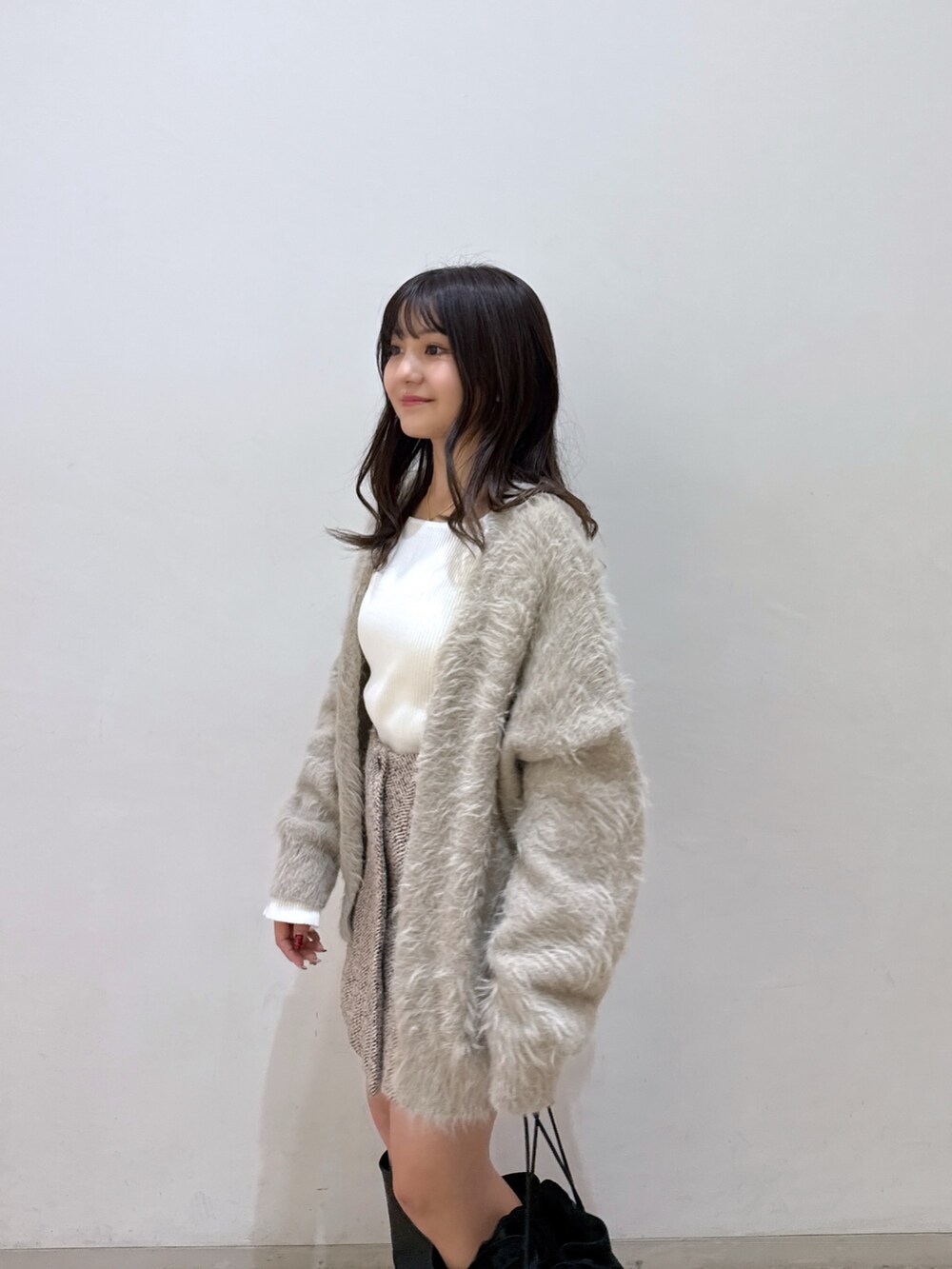 ベージュ系のカーディガン/ボレロ、ホワイト系のニット/セーター、ベージュ系のスカートを着用したレディースの冬コーディネートの5枚目の写真