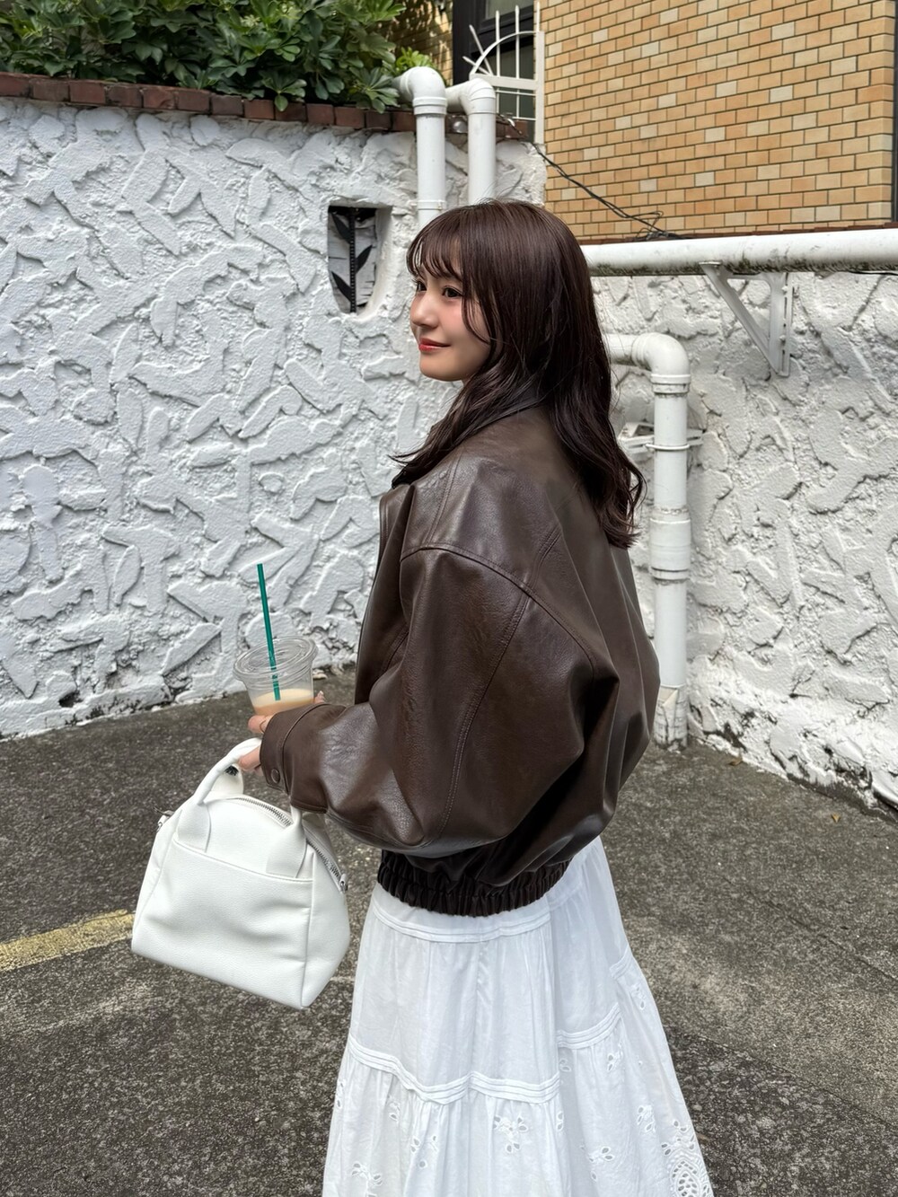 ブラウン系のブルゾン、ホワイト系のスカート、ホワイト系のトートバッグを着用したレディースの秋コーディネートの5枚目の写真
