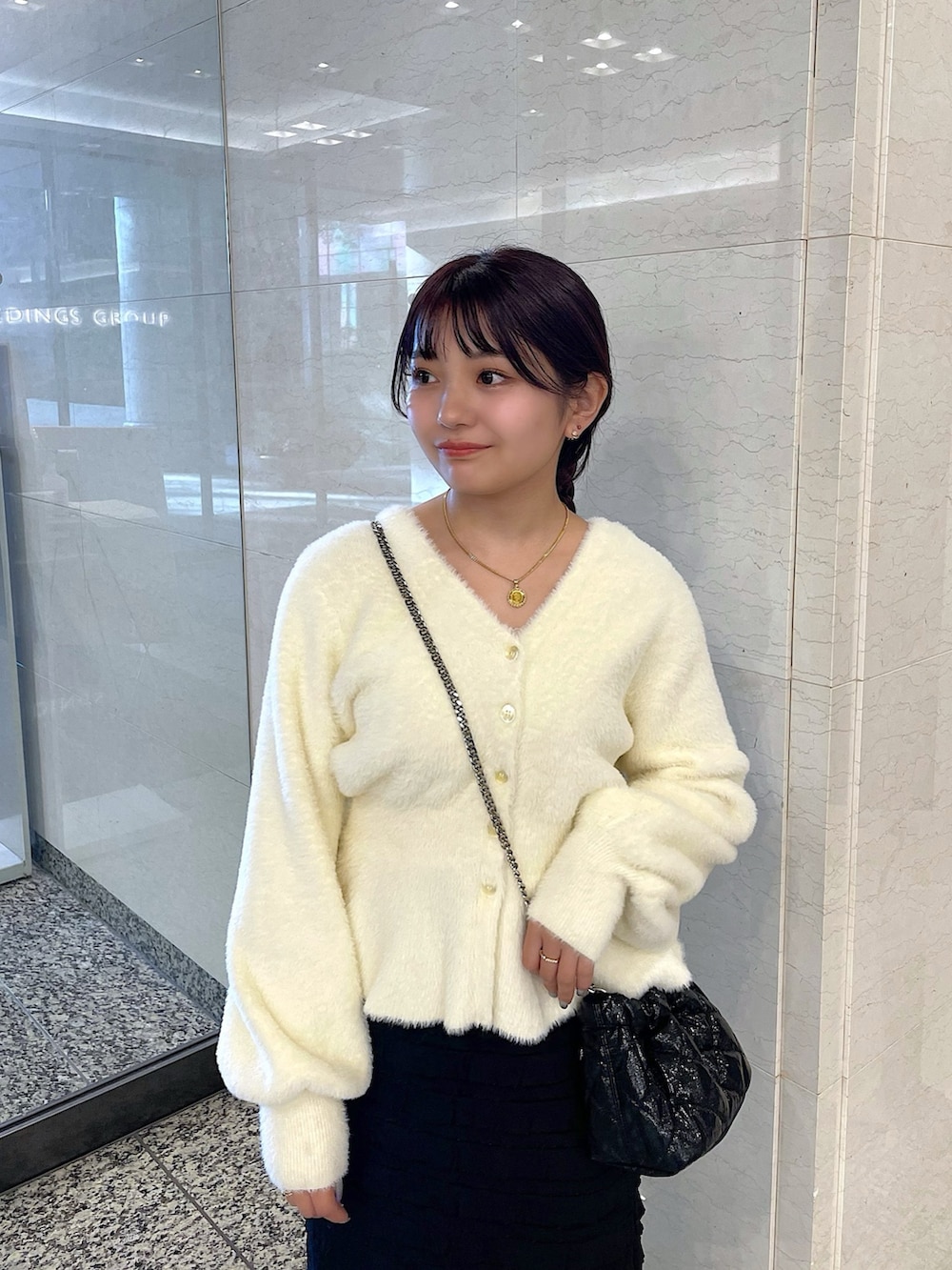 ホワイト系のカーディガン/ボレロ、ブラック系のスカート、ブラック系のショルダーバッグを着用したレディースの冬コーディネートの4枚目の写真