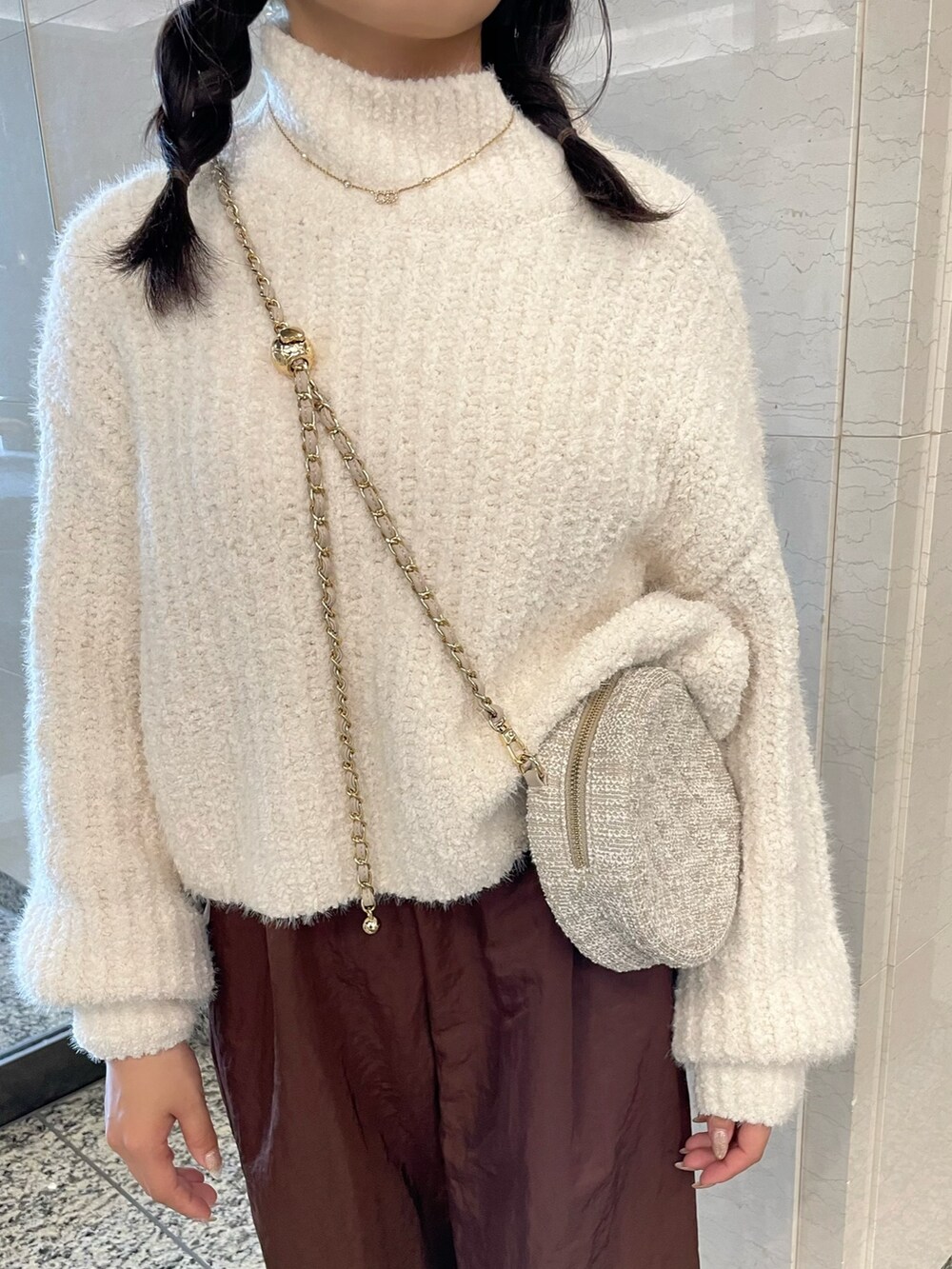 ホワイト系のニット/セーター、ブラウン系のその他パンツ、ベージュ系のショルダーバッグを着用したレディースの秋コーディネートの8枚目の写真