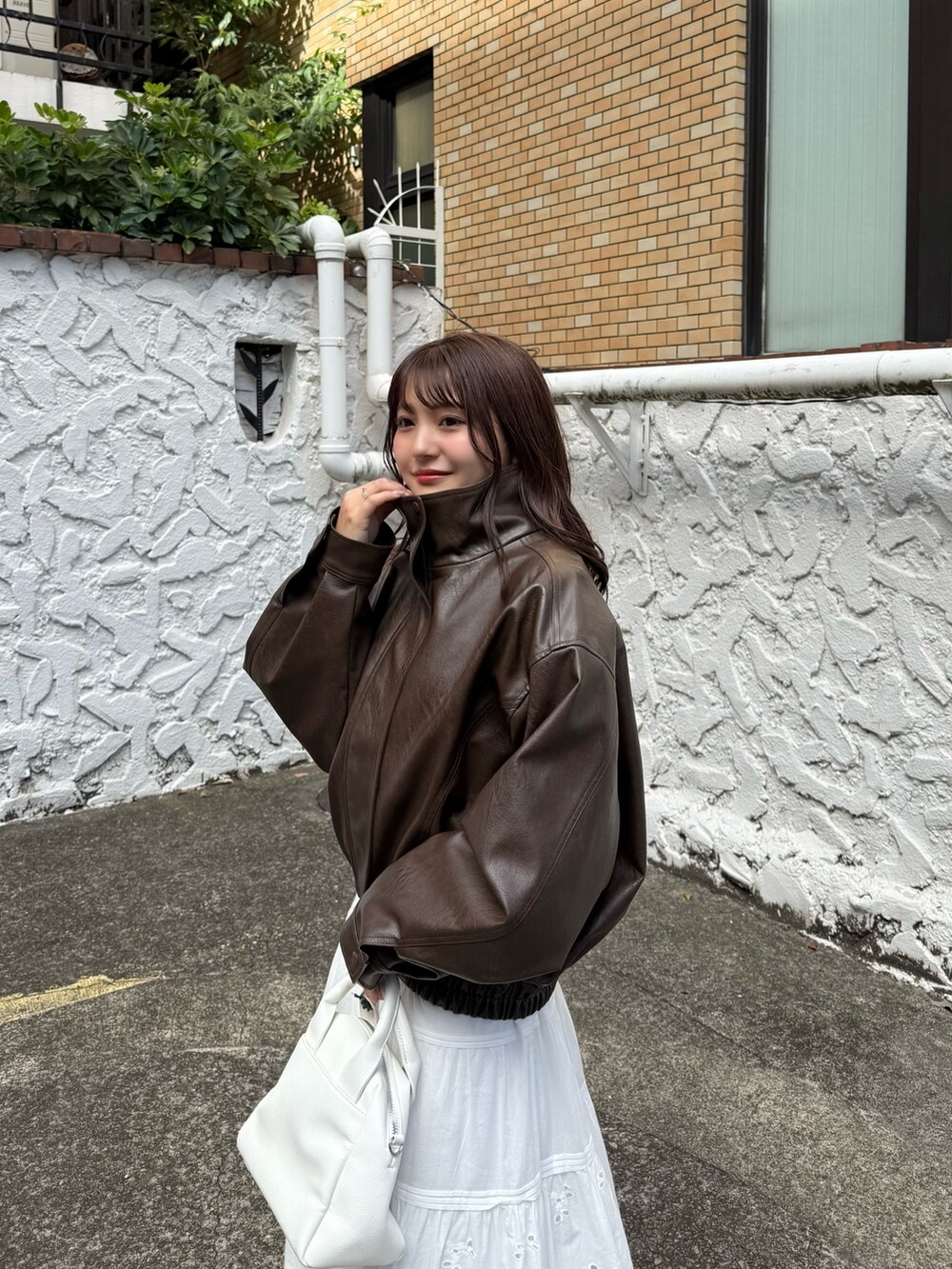 ブラウン系のブルゾン、ホワイト系のスカート、ホワイト系のトートバッグを着用したレディースの秋コーディネートの8枚目の写真