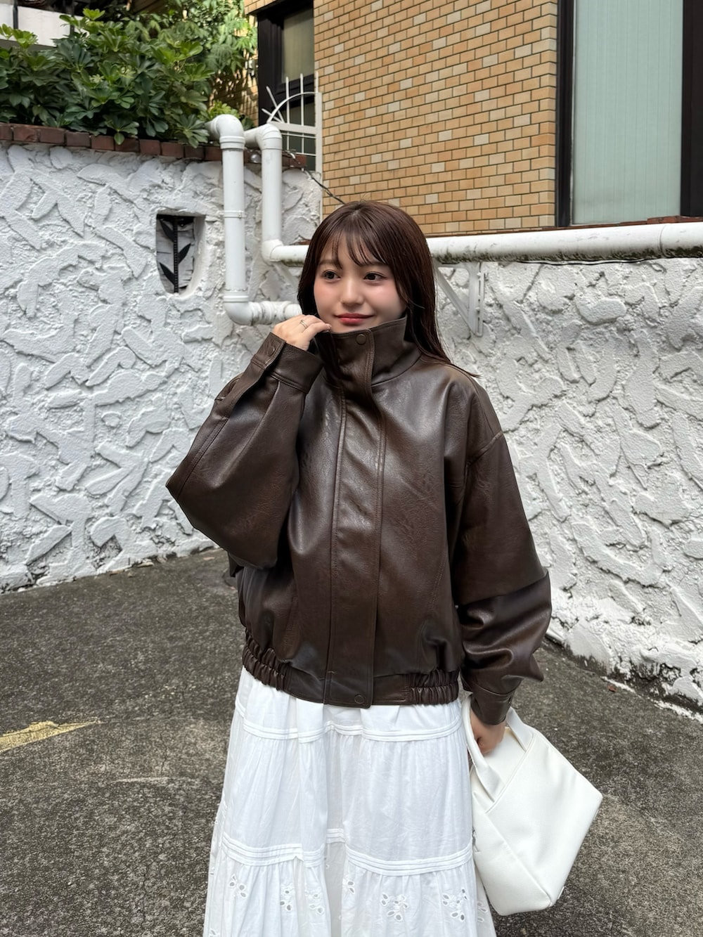 ブラウン系のブルゾン、ホワイト系のスカート、ホワイト系のトートバッグを着用したレディースの秋コーディネートの7枚目の写真
