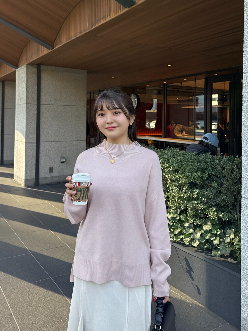 ピンク系のニット/セーター、ホワイト系のスカート、ブラック系のブーツを着用したレディースの冬コーディネートの4枚目の写真
