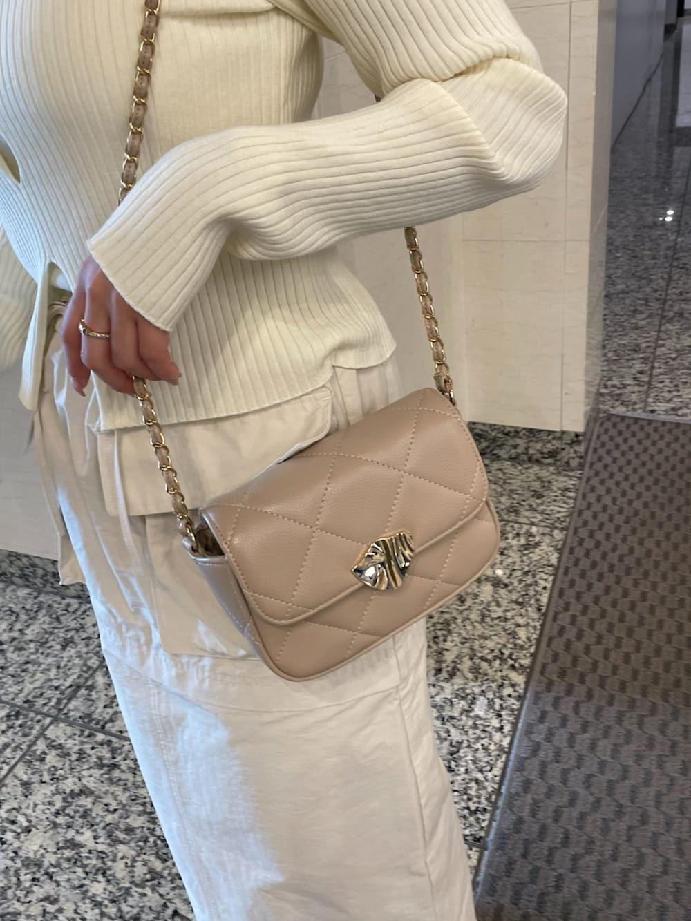 ベージュ系のトレンチコート、ホワイト系のニット/セーター、ベージュ系のショルダーバッグを着用したレディースの春コーディネートの9枚目の写真