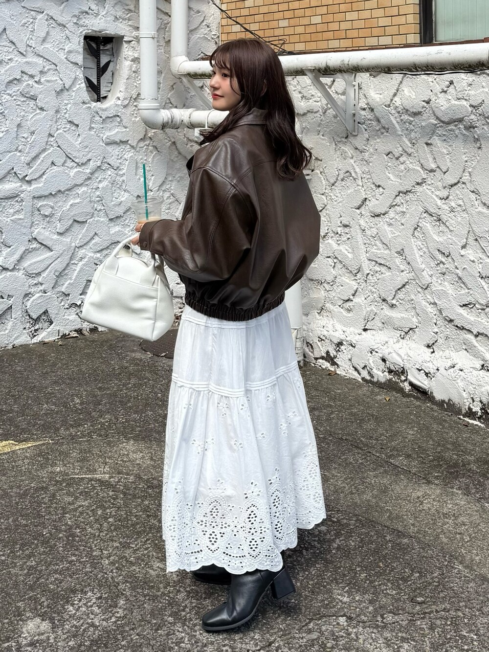 ブラウン系のブルゾン、ホワイト系のスカート、ホワイト系のトートバッグを着用したレディースの秋コーディネートの2枚目の写真