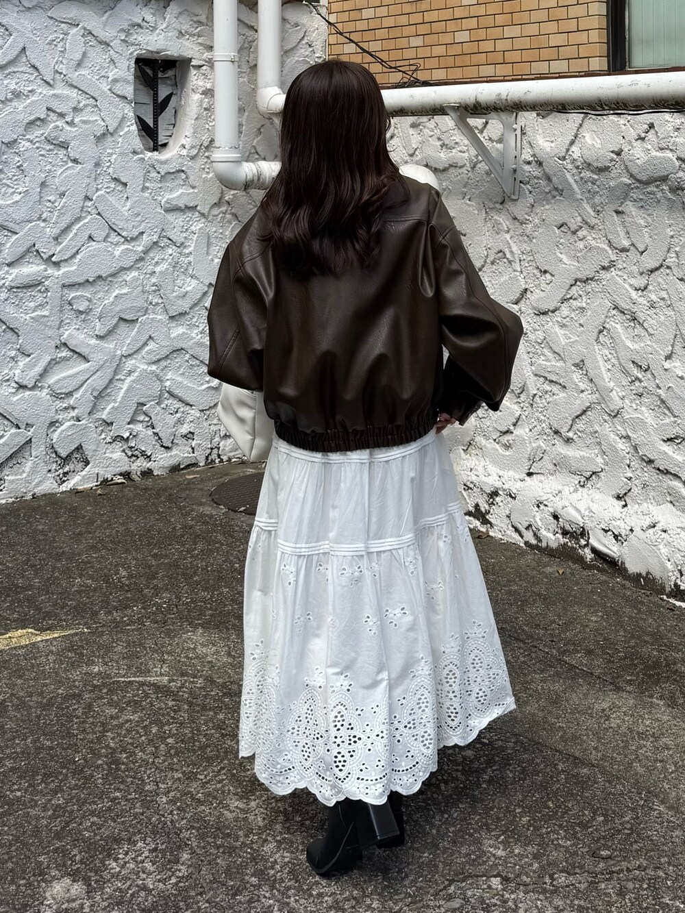 ブラウン系のブルゾン、ホワイト系のスカート、ホワイト系のトートバッグを着用したレディースの秋コーディネートの3枚目の写真