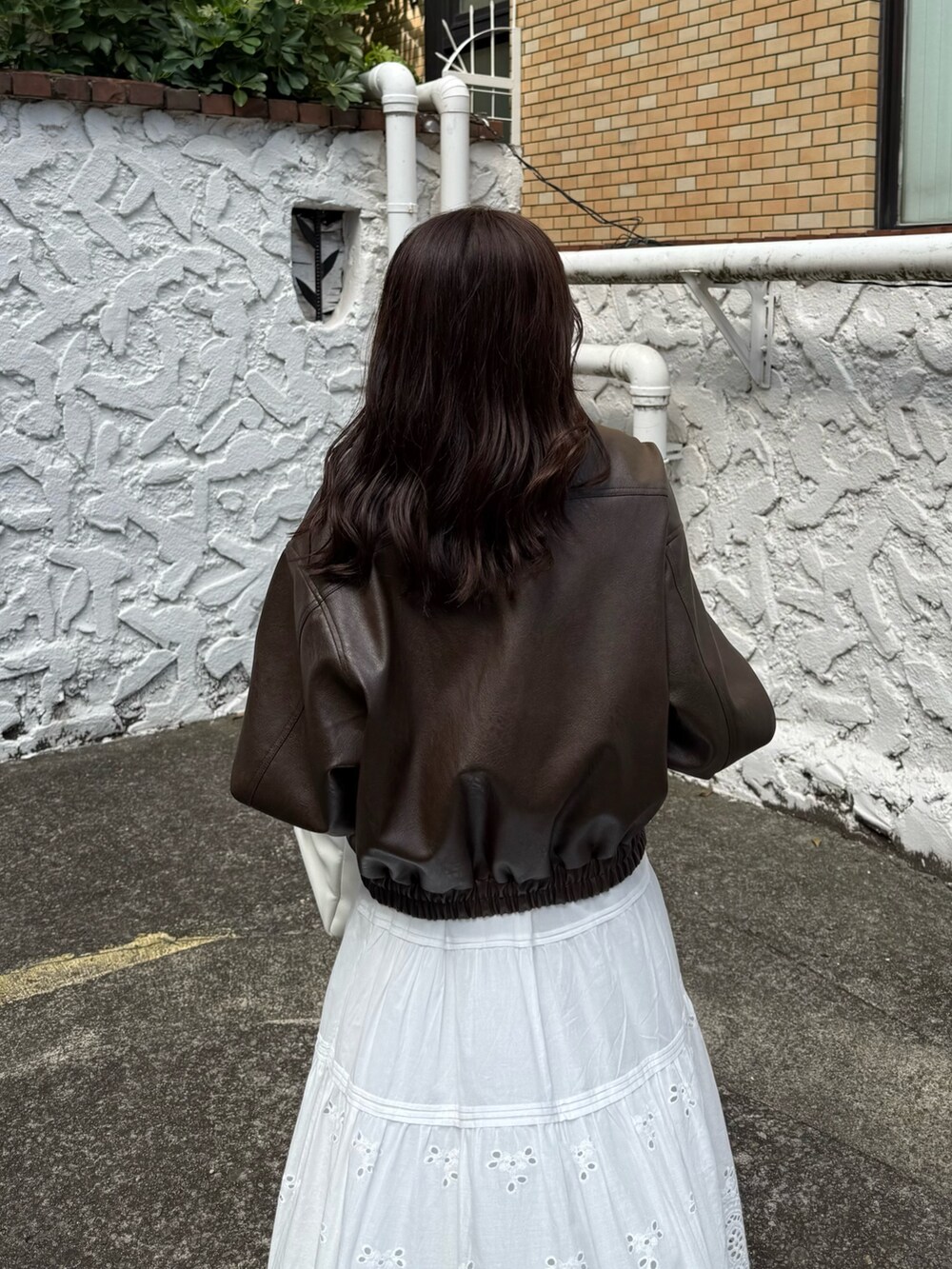 ブラウン系のブルゾン、ホワイト系のスカート、ホワイト系のトートバッグを着用したレディースの秋コーディネートの6枚目の写真
