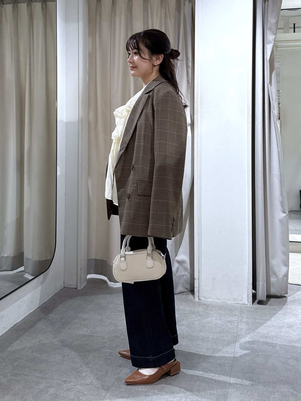 ブラウン系のテーラードジャケット、ホワイト系のシャツ/ブラウス、ブルー系のデニムパンツを着用したレディースの秋コーディネートの2枚目の写真