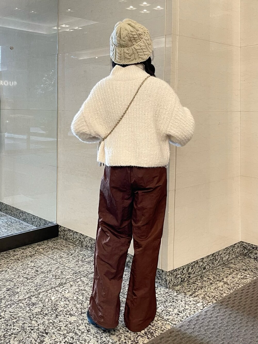ホワイト系のニット/セーター、ブラウン系のその他パンツ、ベージュ系のショルダーバッグを着用したレディースの秋コーディネートの3枚目の写真