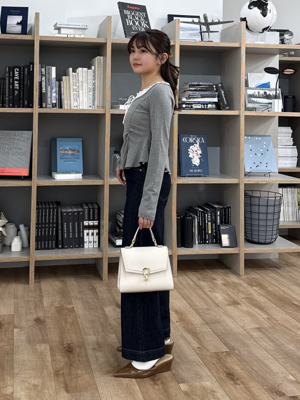 グレー系のTシャツ/カットソー、ブラウン系のパンプス、ホワイト系のトートバッグを着用したレディースの冬コーディネートの5枚目の写真