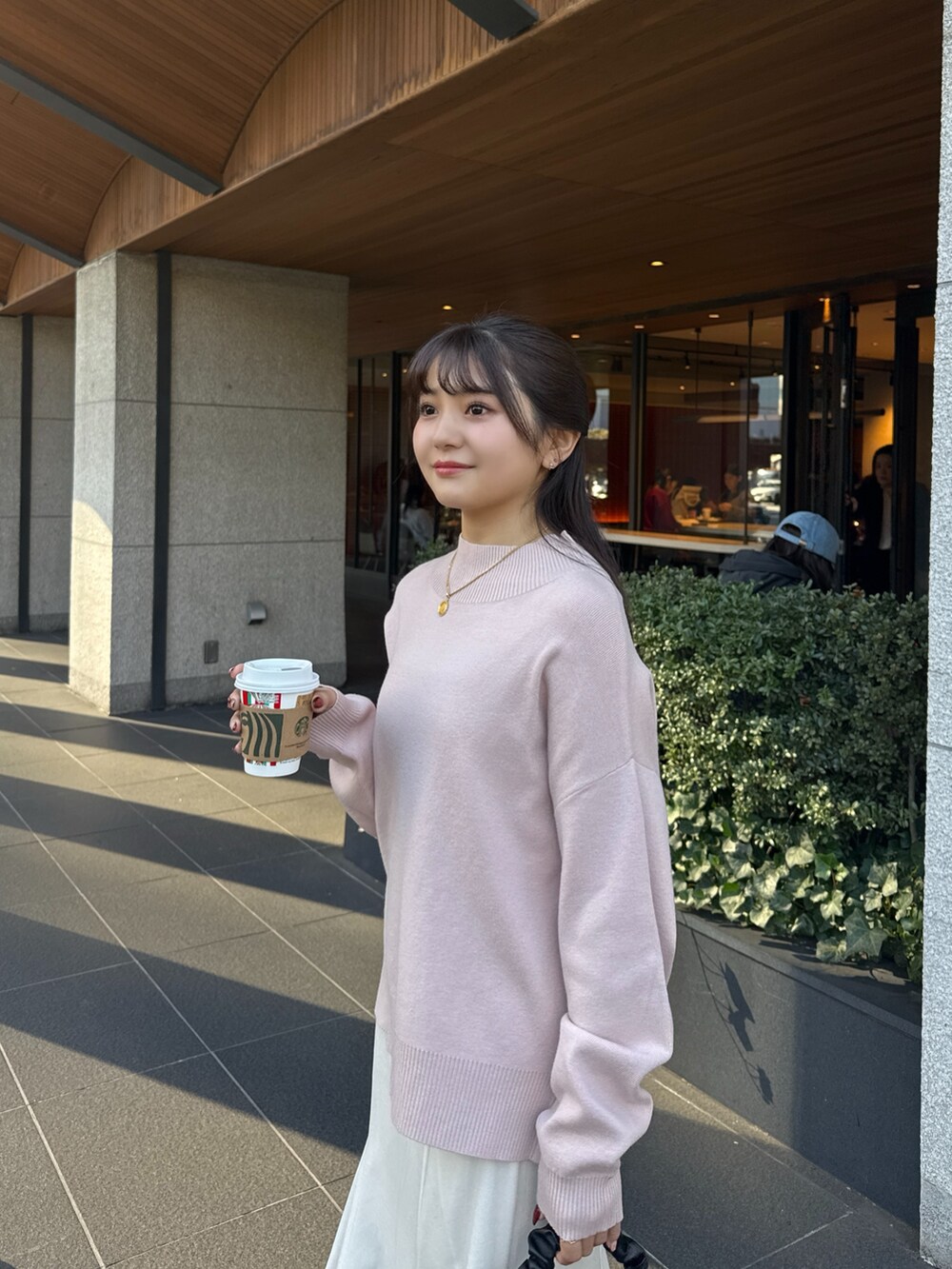 ピンク系のニット/セーター、ホワイト系のスカート、ブラック系のブーツを着用したレディースの冬コーディネートの5枚目の写真