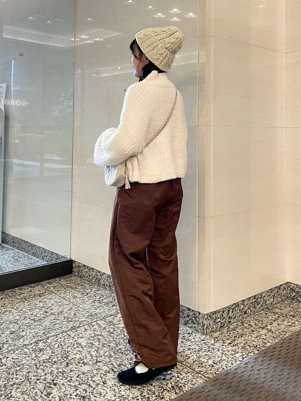 ホワイト系のニット/セーター、ブラウン系のその他パンツ、ベージュ系のショルダーバッグを着用したレディースの秋コーディネートの2枚目の写真