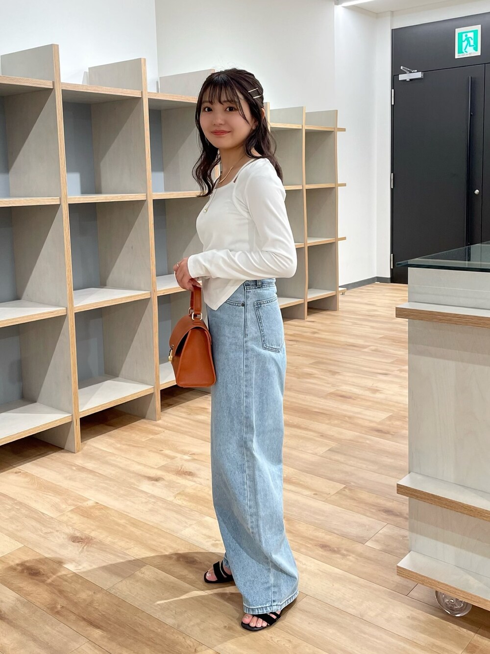 ホワイト系のTシャツ/カットソー、ブルー系のデニムパンツ、ブラウン系のショルダーバッグを着用したレディースの夏コーディネートの2枚目の写真