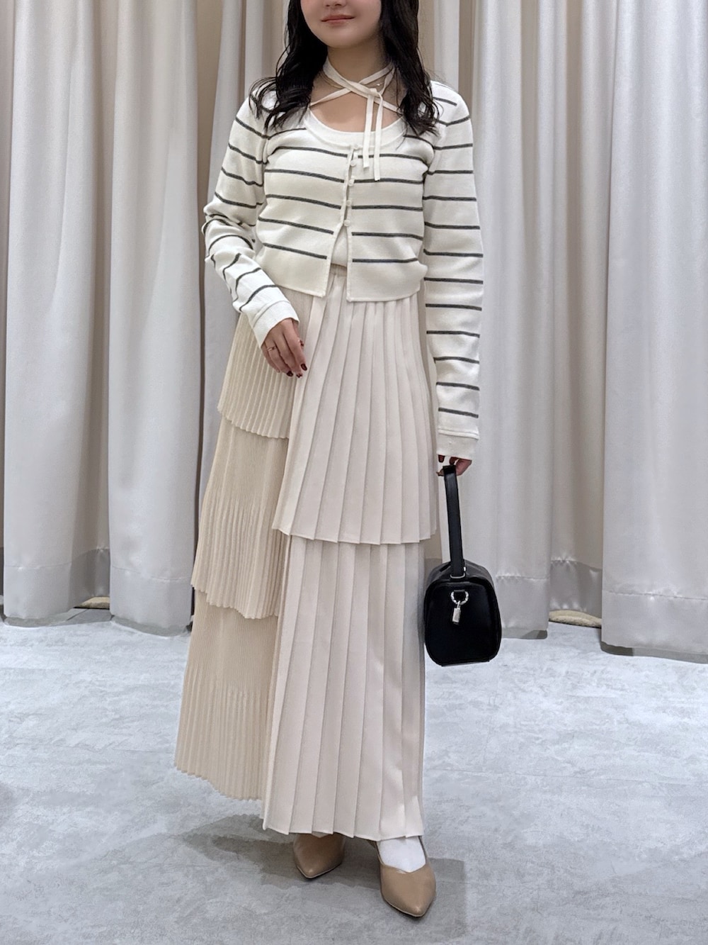 ホワイト系のニット/セーター、ホワイト系のスカート、ブラック系のハンドバッグを着用したレディースの春コーディネートの4枚目の写真