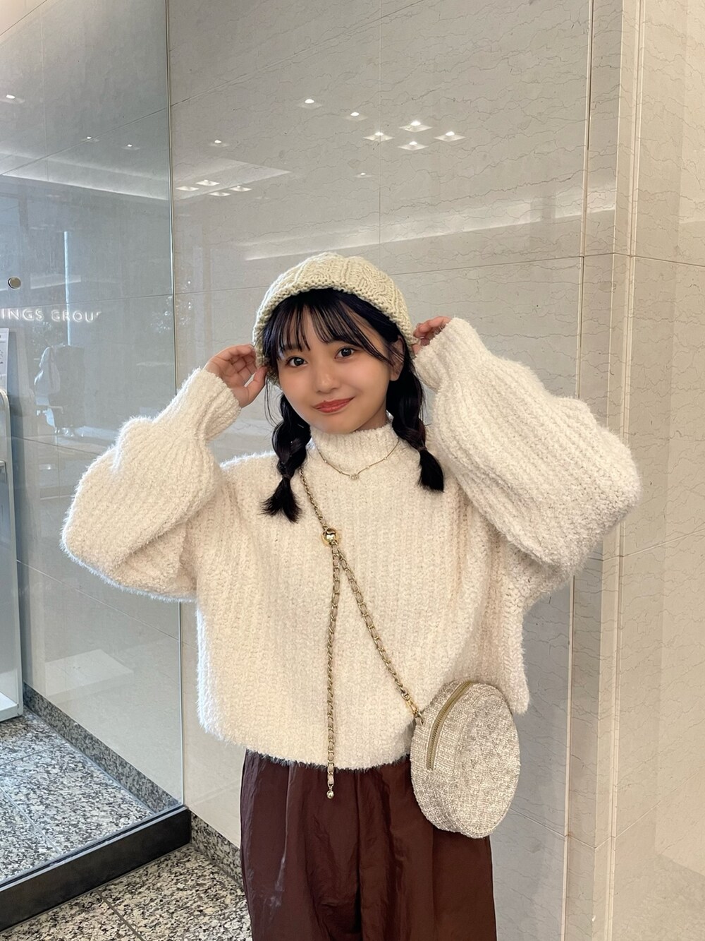 ホワイト系のニット/セーター、ブラウン系のその他パンツ、ベージュ系のショルダーバッグを着用したレディースの秋コーディネートの4枚目の写真