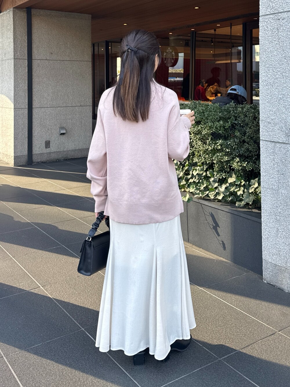 ピンク系のニット/セーター、ホワイト系のスカート、ブラック系のブーツを着用したレディースの冬コーディネートの3枚目の写真