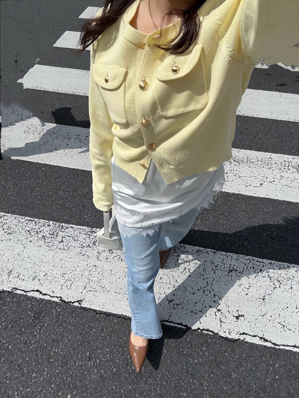 ホワイト系のニット/セーター、ホワイト系のキャミソール、ブルー系のデニムパンツを着用したレディースの春コーディネートの5枚目の写真