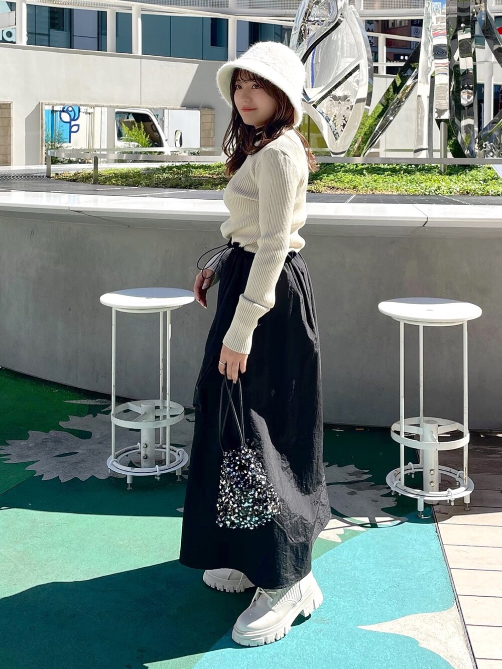 ホワイト系のワンピース、ブラック系のハンドバッグ、ホワイト系のブーツを着用したレディースの秋コーディネートの2枚目の写真