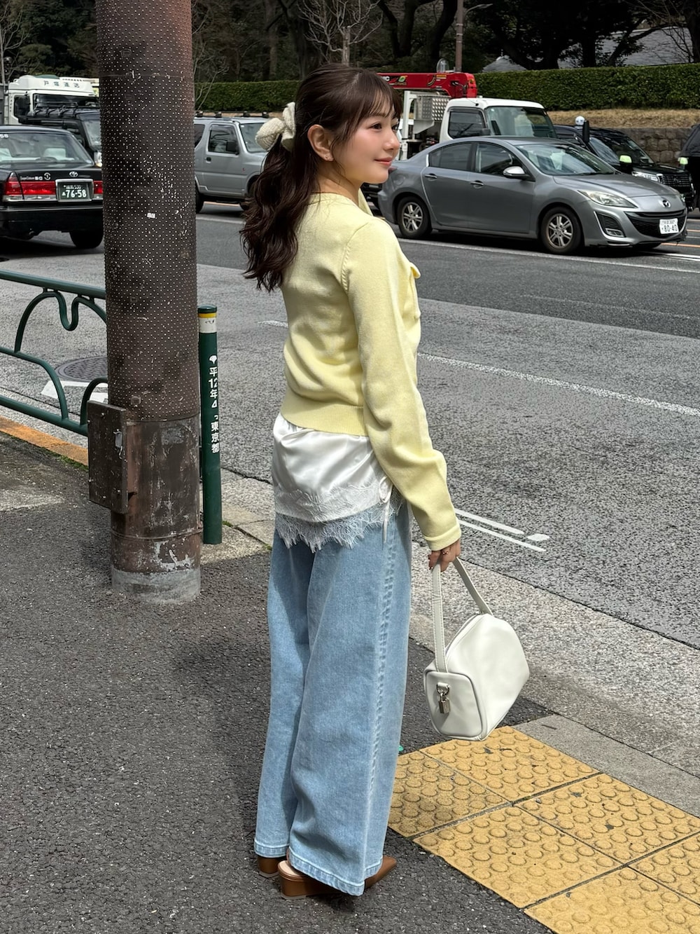 ホワイト系のニット/セーター、ホワイト系のキャミソール、ブルー系のデニムパンツを着用したレディースの春コーディネートの2枚目の写真