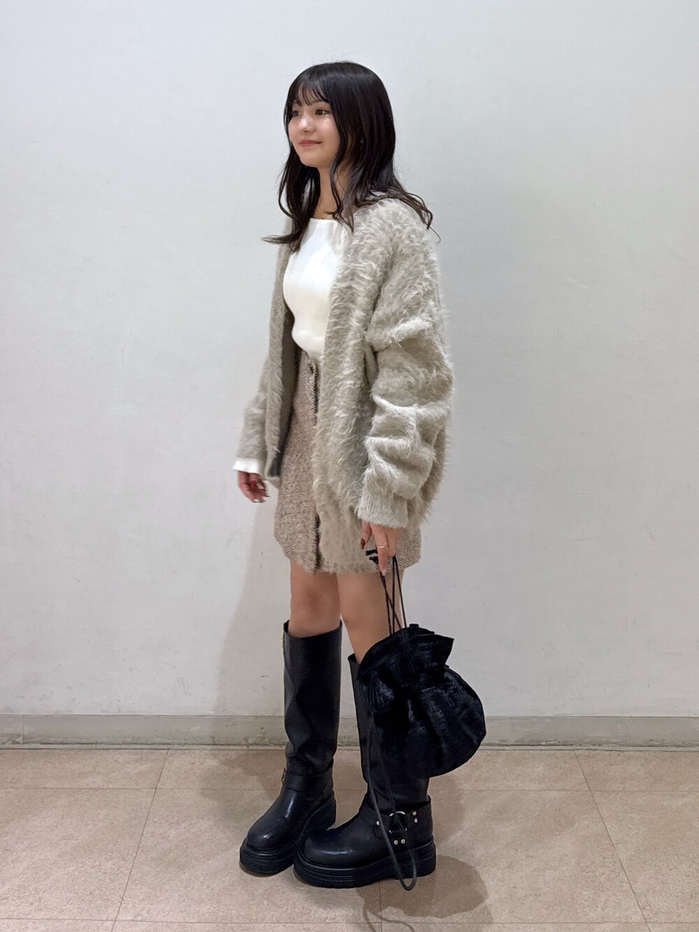 ベージュ系のカーディガン/ボレロ、ホワイト系のニット/セーター、ベージュ系のスカートを着用したレディースの冬コーディネートの2枚目の写真