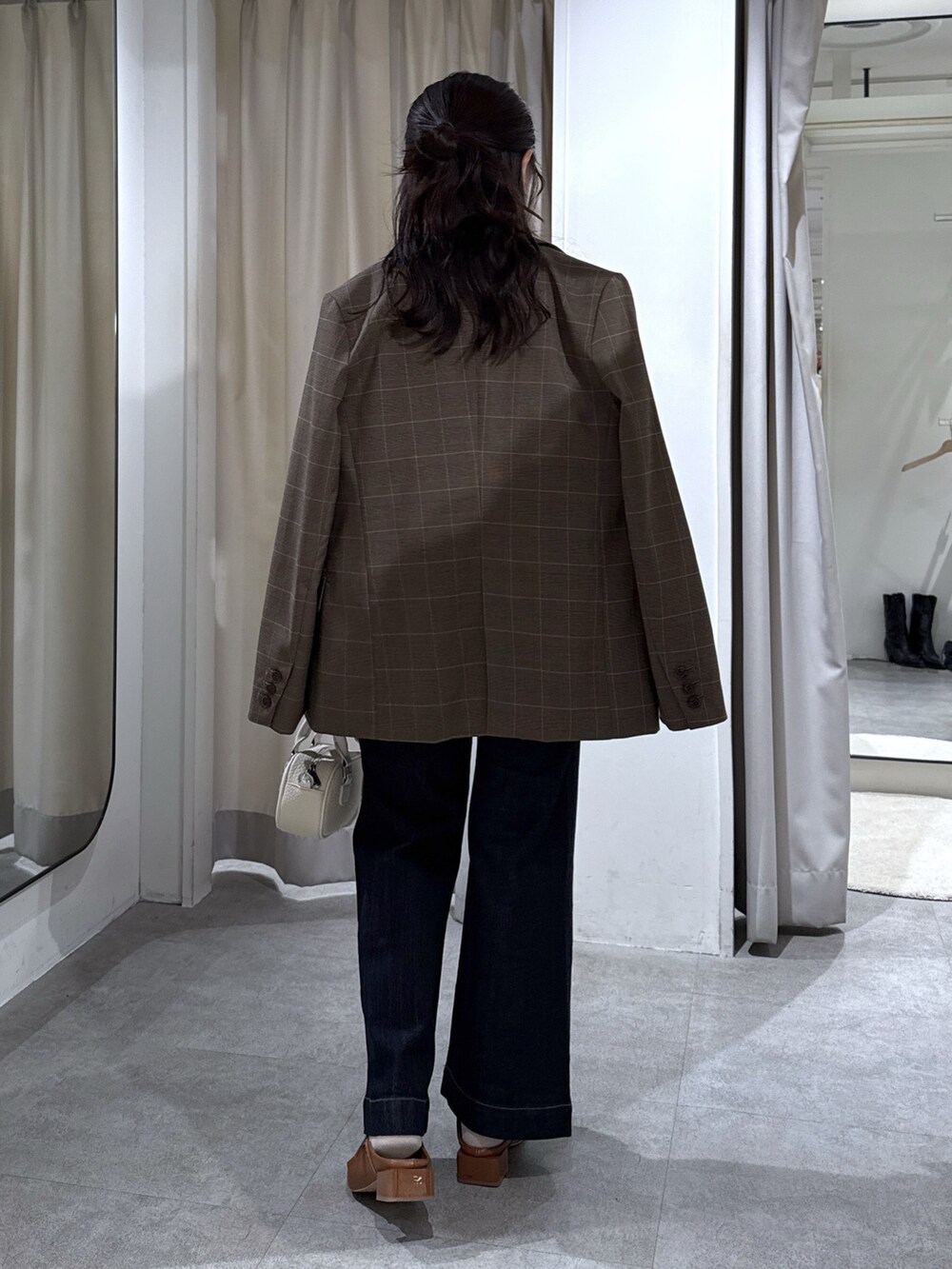 ブラウン系のテーラードジャケット、ホワイト系のシャツ/ブラウス、ブルー系のデニムパンツを着用したレディースの秋コーディネートの3枚目の写真