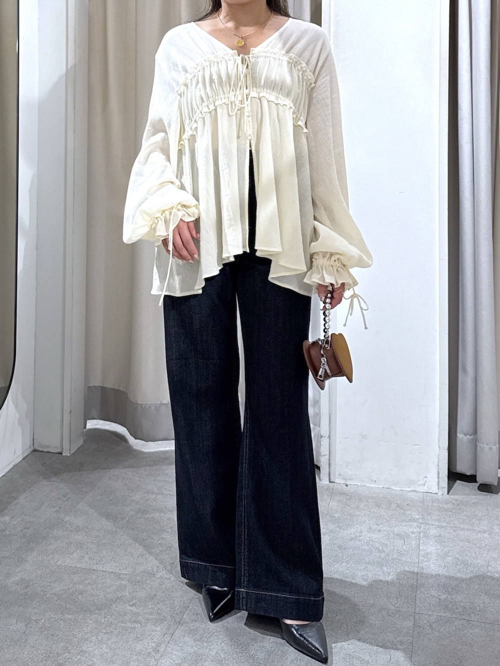 ホワイト系のシャツ/ブラウス、ブルー系のデニムパンツ、ブラック系のパンプスを着用したレディースの秋コーディネートの4枚目の写真