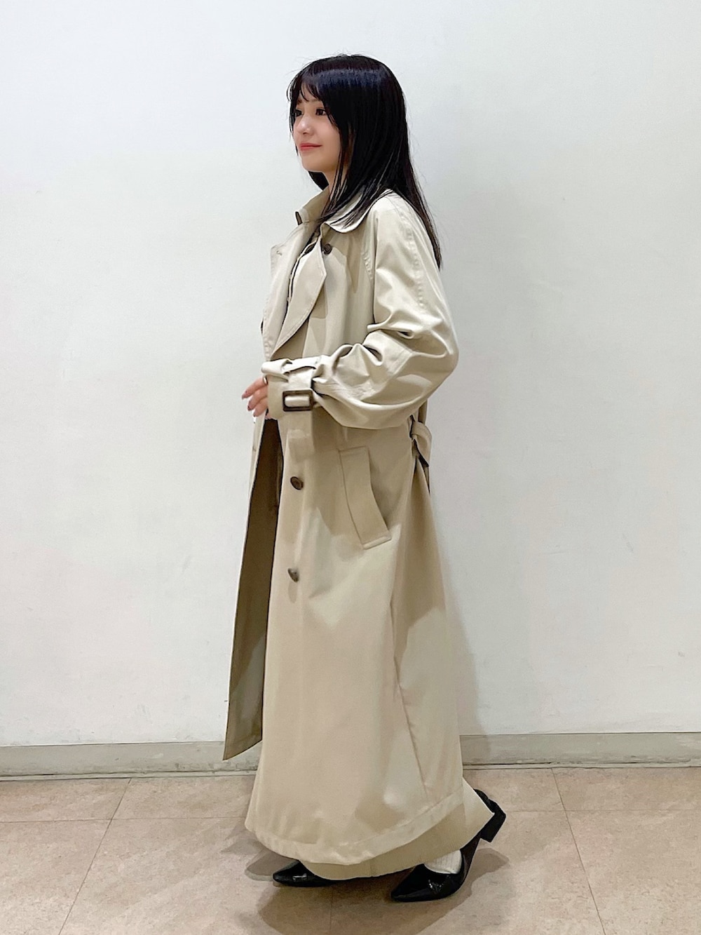 ベージュ系のトレンチコート、ベージュ系のカーディガン/ボレロ、ベージュ系のワンピースを着用したレディースの春コーディネートの2枚目の写真