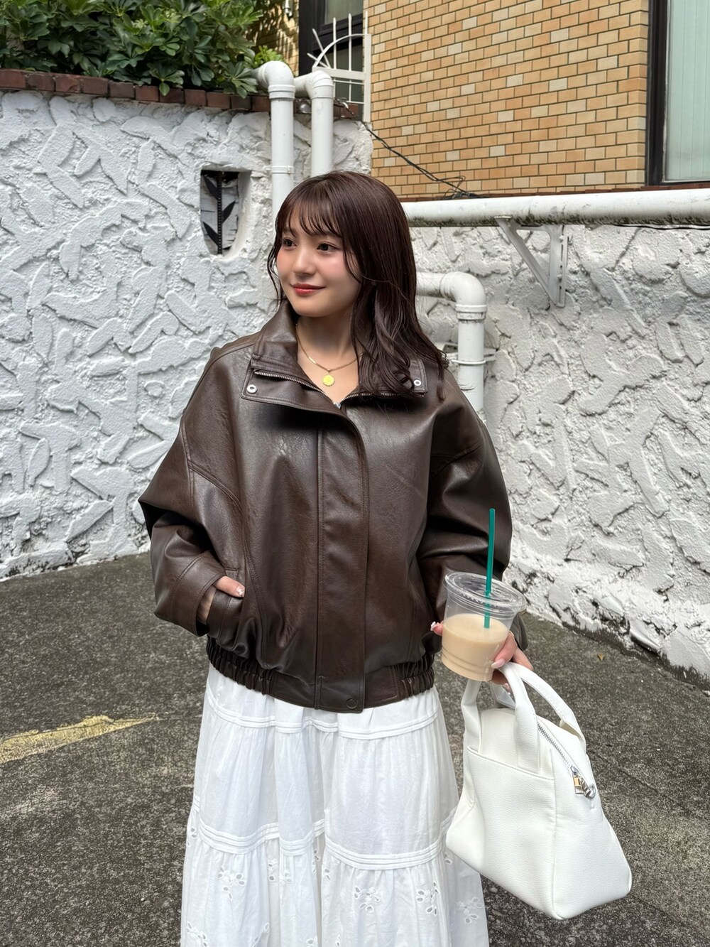 ブラウン系のブルゾン、ホワイト系のスカート、ホワイト系のトートバッグを着用したレディースの秋コーディネートの4枚目の写真