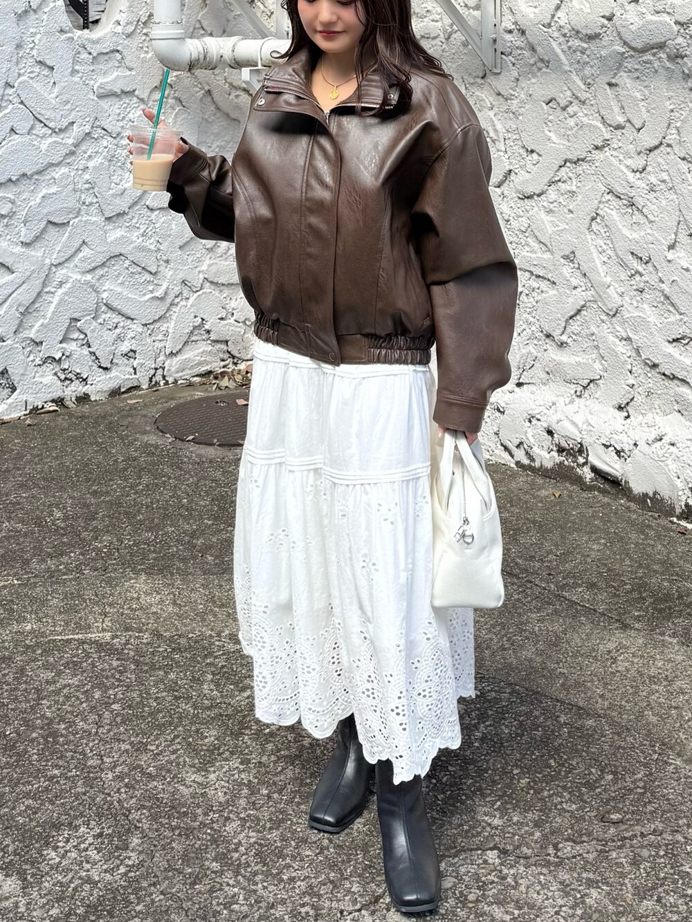 ブラウン系のブルゾン、ホワイト系のスカート、ホワイト系のトートバッグを着用したレディースの秋コーディネートの9枚目の写真
