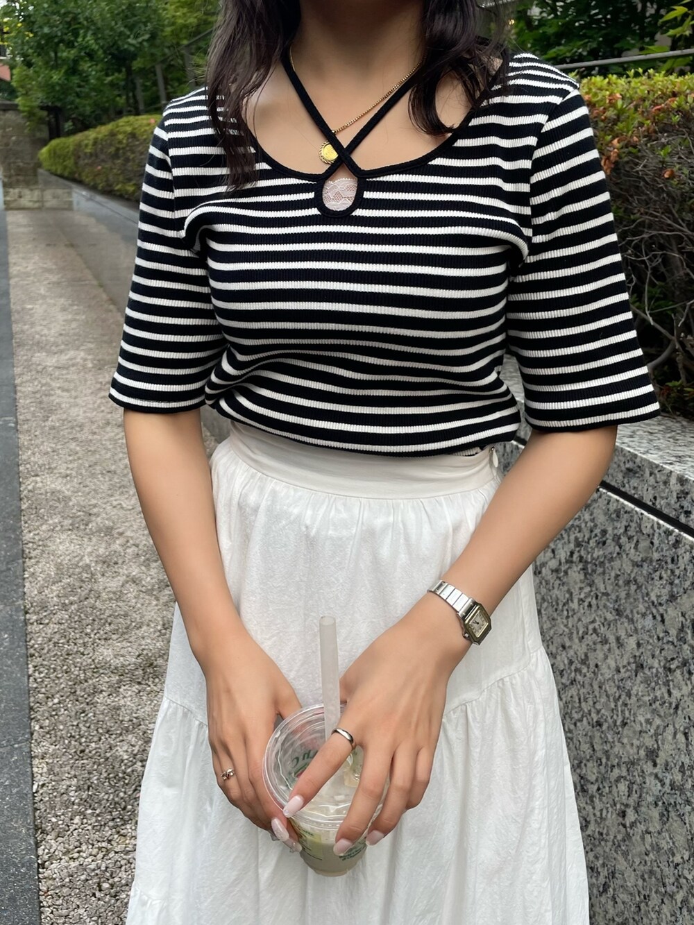 ホワイト系のスカート、ホワイト系のTシャツ/カットソー、ブラック系のサンダルを着用したレディースの夏コーディネートの4枚目の写真