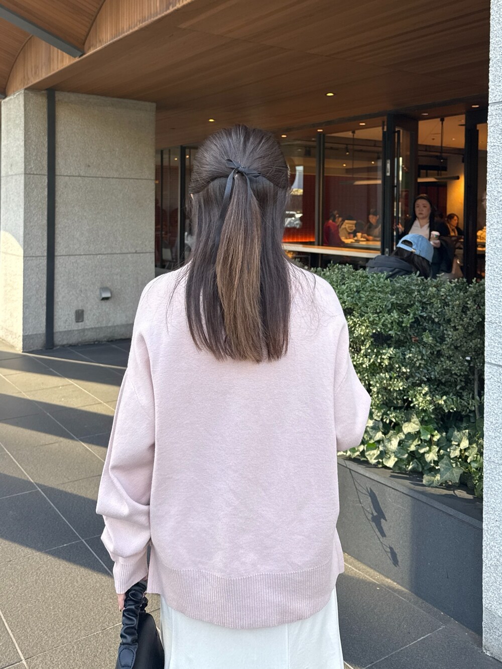 ピンク系のニット/セーター、ホワイト系のスカート、ブラック系のブーツを着用したレディースの冬コーディネートの6枚目の写真