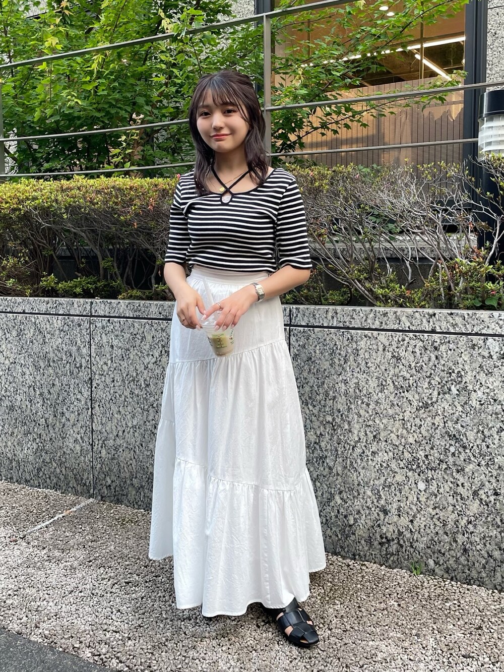 ホワイト系のスカート、ホワイト系のTシャツ/カットソー、ブラック系のサンダルを着用したレディースの夏コーディネートの2枚目の写真