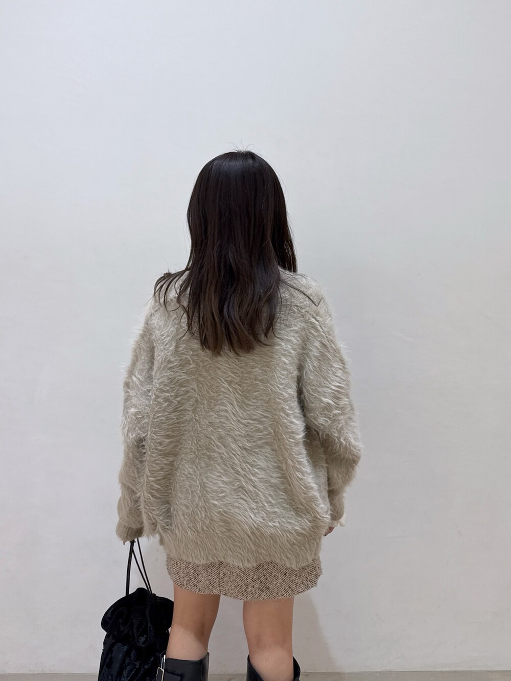 ベージュ系のカーディガン/ボレロ、ホワイト系のニット/セーター、ベージュ系のスカートを着用したレディースの冬コーディネートの6枚目の写真