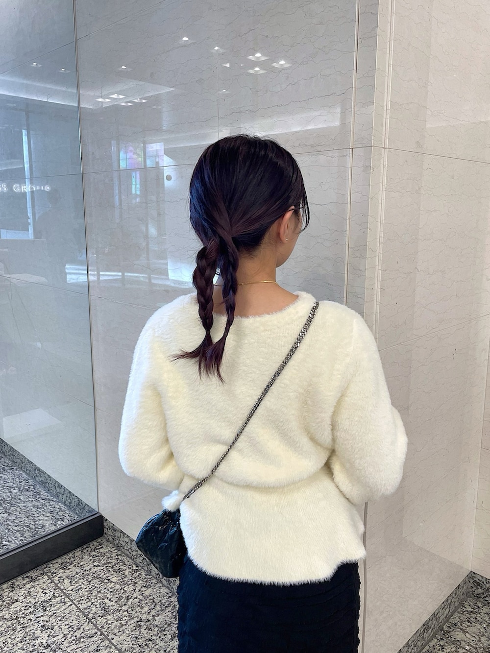 ホワイト系のカーディガン/ボレロ、ブラック系のスカート、ブラック系のショルダーバッグを着用したレディースの冬コーディネートの6枚目の写真