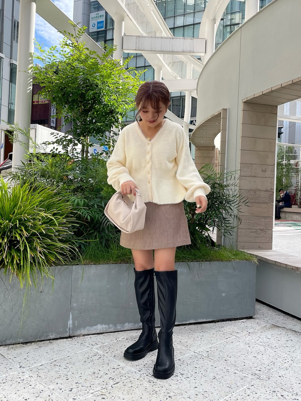 ホワイト系のカーディガン/ボレロ、ホワイト系のハンドバッグ、ブラック系のブーツを着用したレディースの秋コーディネートの2枚目の写真