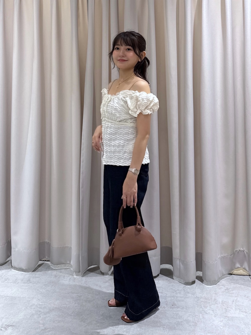 ブラウン系のサンダル、ブルー系のデニムパンツ、ブラウン系のボストンバッグを着用したレディースの夏コーディネートの2枚目の写真