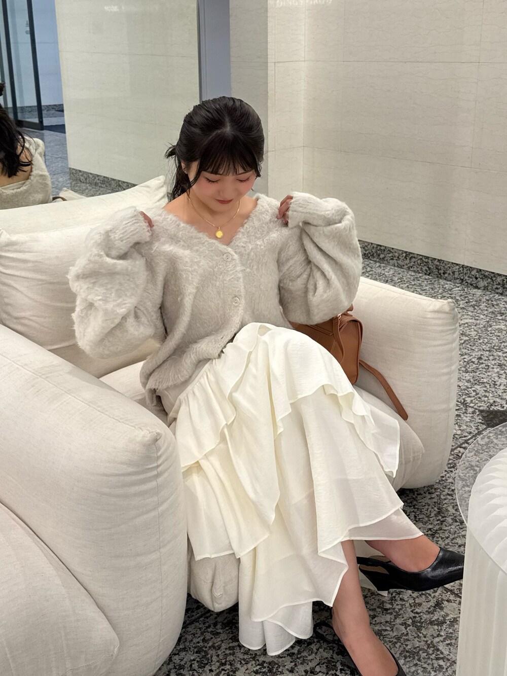 ベージュ系のニット/セーター、ホワイト系のスカート、ベージュ系のトートバッグを着用したレディースの秋コーディネートの6枚目の写真