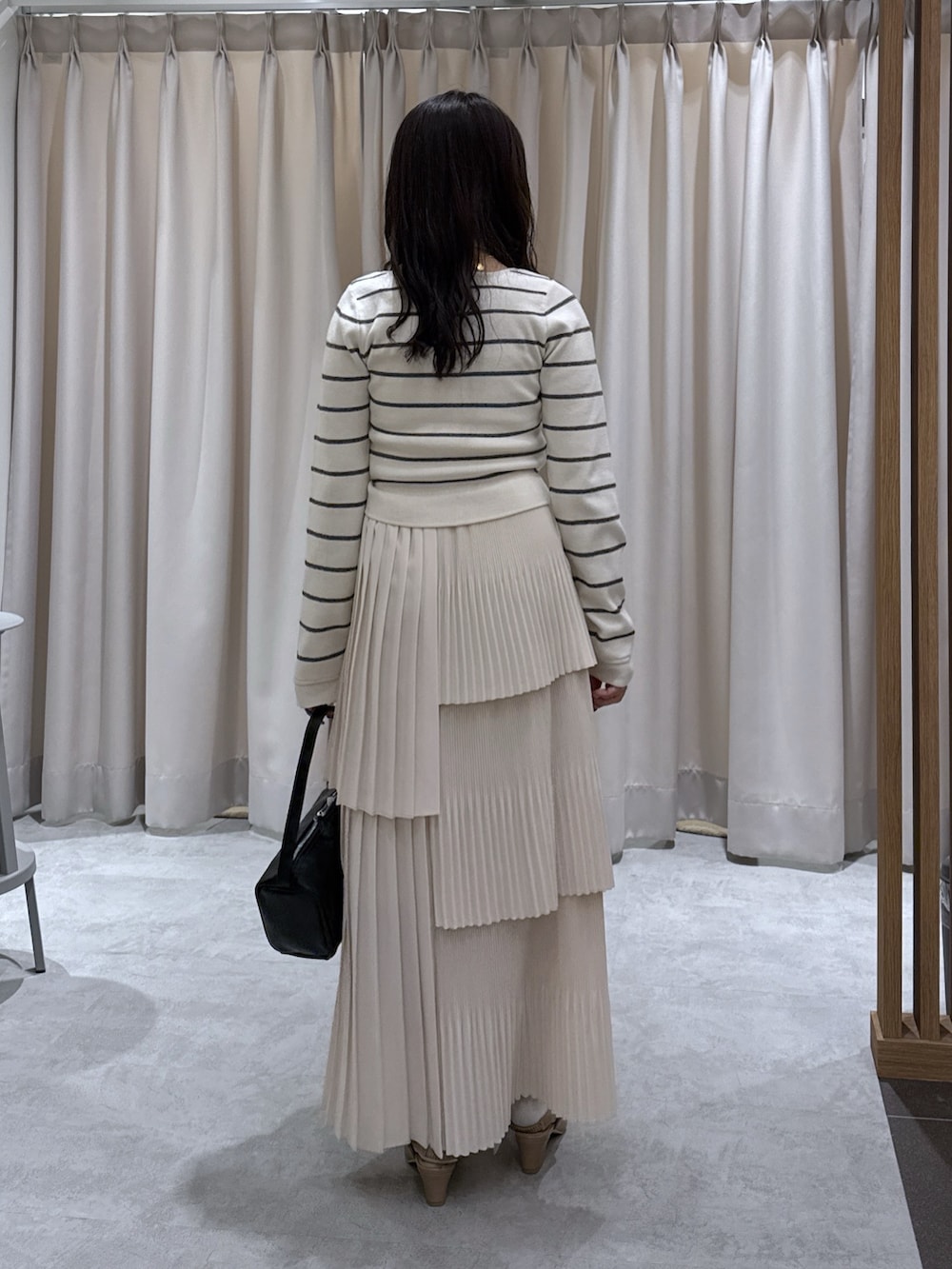 ホワイト系のニット/セーター、ホワイト系のスカート、ブラック系のハンドバッグを着用したレディースの春コーディネートの3枚目の写真
