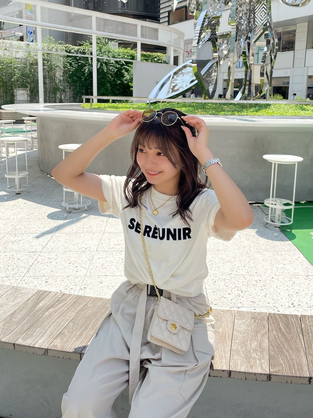 ベージュ系のカーゴパンツ、ホワイト系のTシャツ/カットソー、ホワイト系のショルダーバッグを着用したレディースの夏コーディネートの3枚目の写真